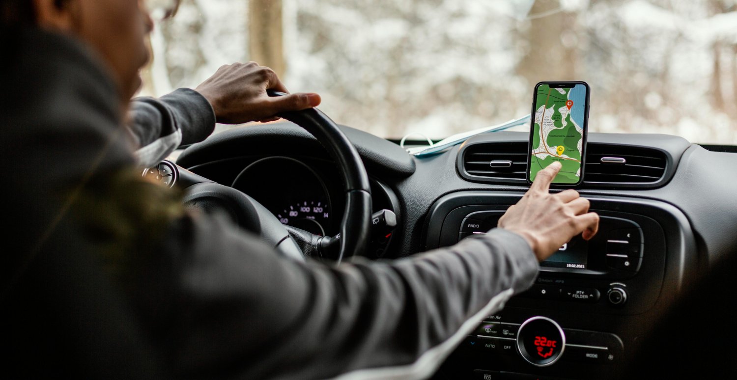 A driver intently navigating the road, using a map shown on the car's dashboard screen for directions.